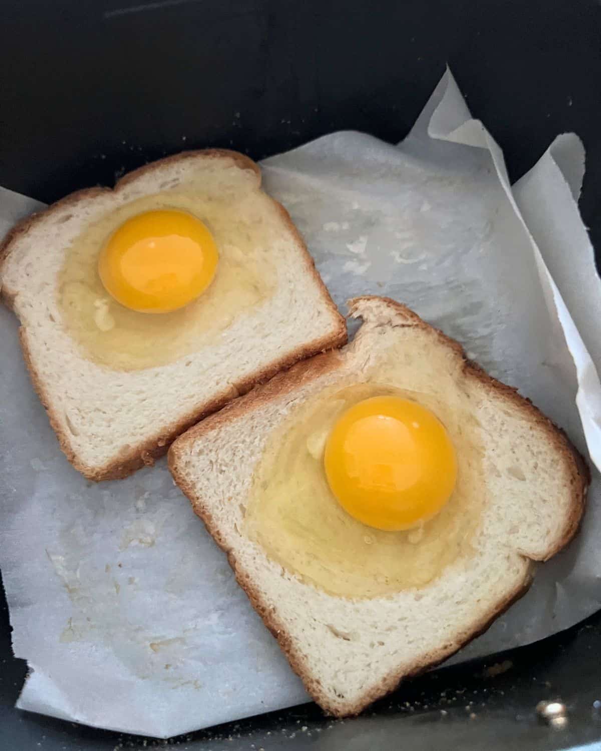 White bread with an egg on top in air fryer basket. 