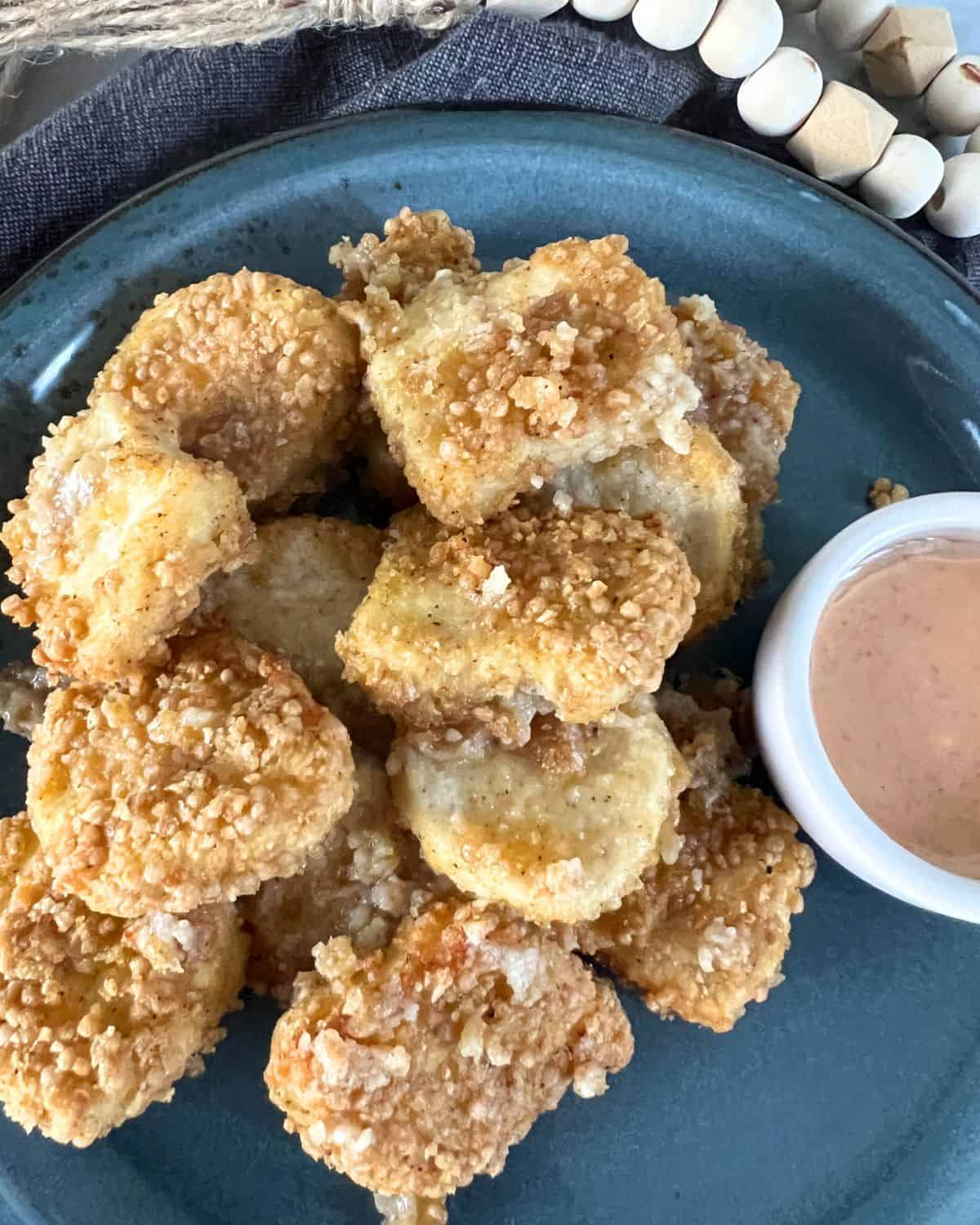 Air fryer chicken nuggets on a pblue plate next to bang bang sauce. 