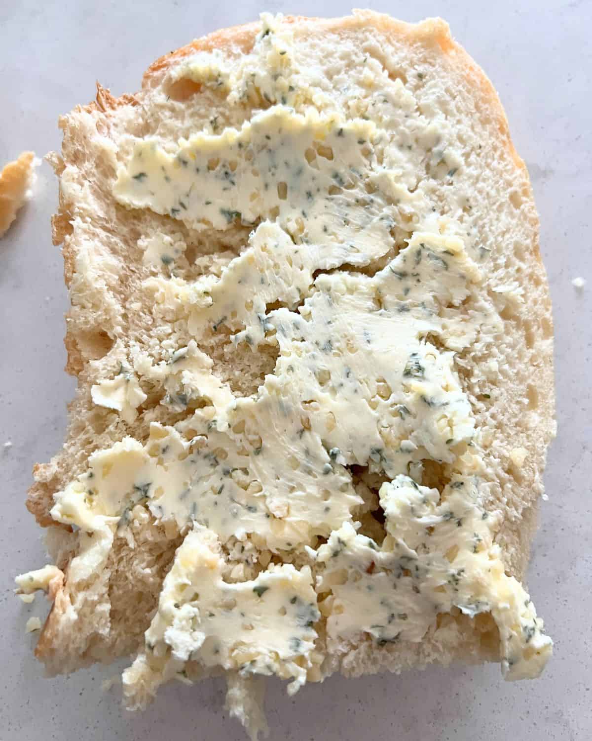 Butter, garlic, and seasoning mixed together in a bowl spread on the bread. 