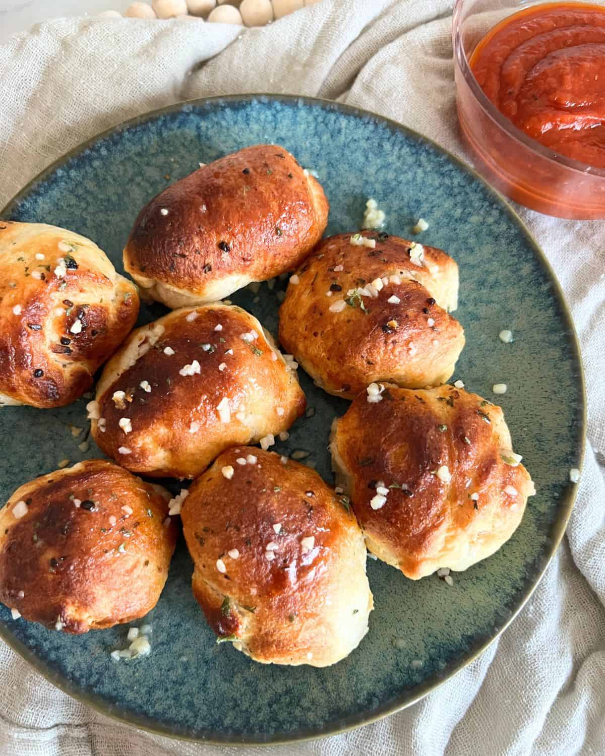 Finished air fryer pizza bombs on a blue plate garnished with garlic butter. 