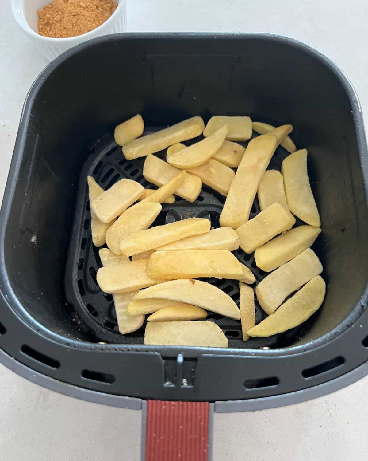 Frozen french fries in air fryer basket. 