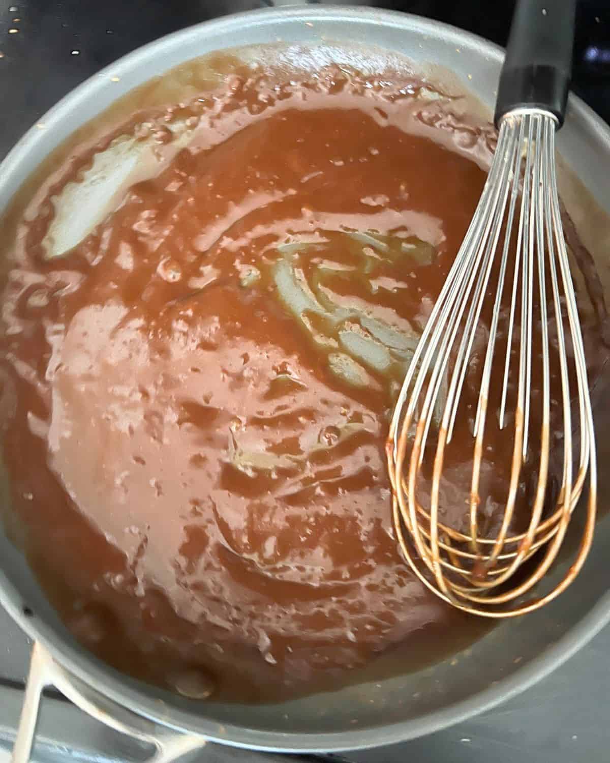 Brown gravy mixed together with water in a skillet. 