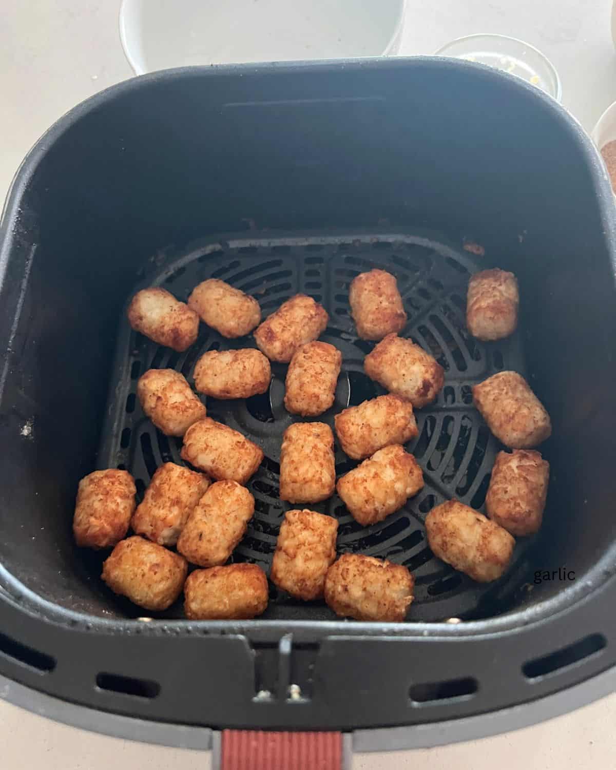 Tater tots in air fryer basket. 