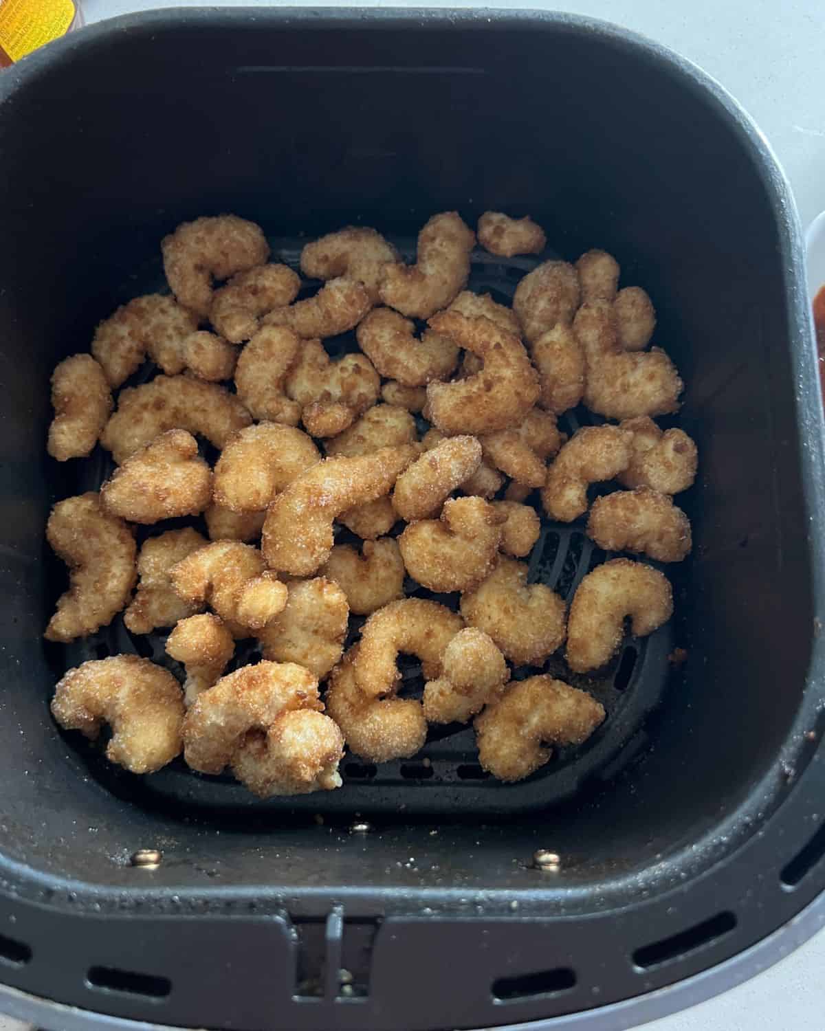 Popcorn shrimp in air fryer basket. 