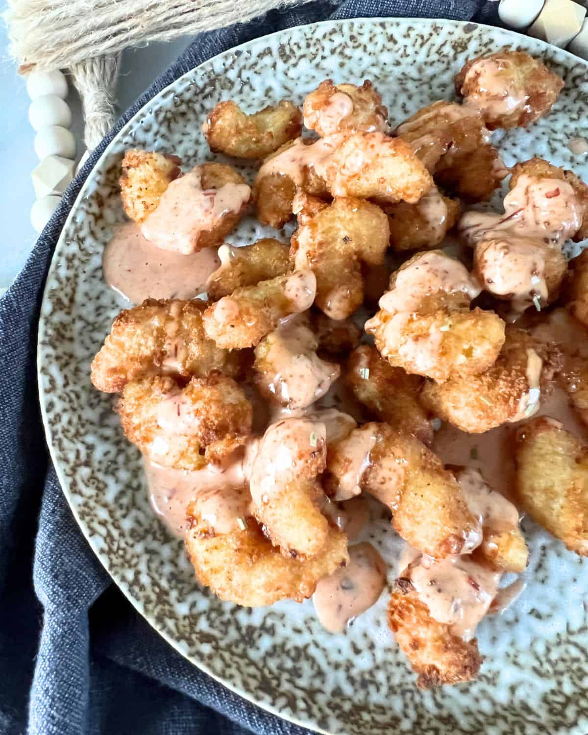Air fryer popcorn shrimp topped with bang bang sauce. 