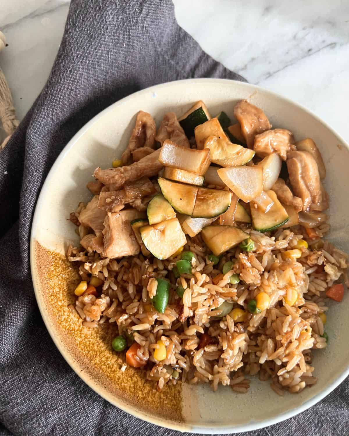 Blackstone fried rice next to chicken and vegetables on plate. 