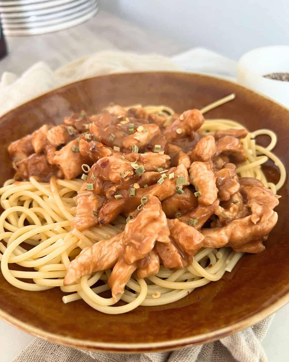 Coated chicken with peanut sauce over noodles. 