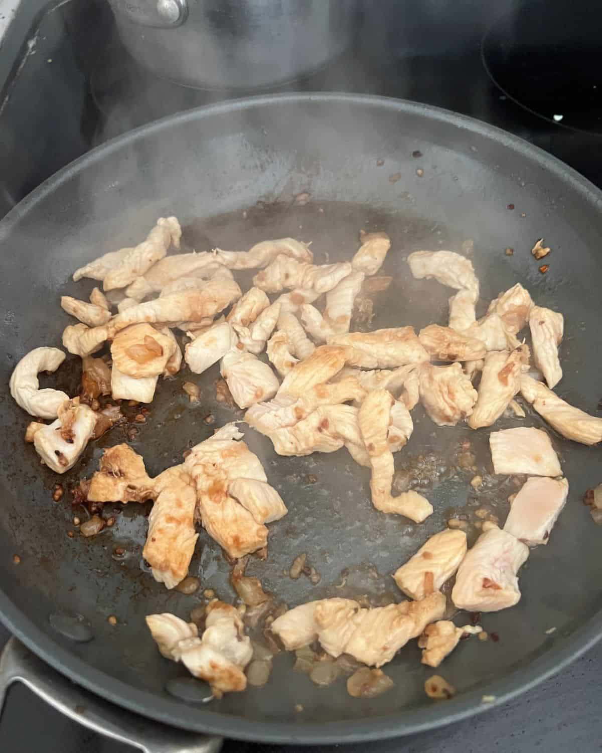 Cooked chicken, onions, and garlic in a pan. 