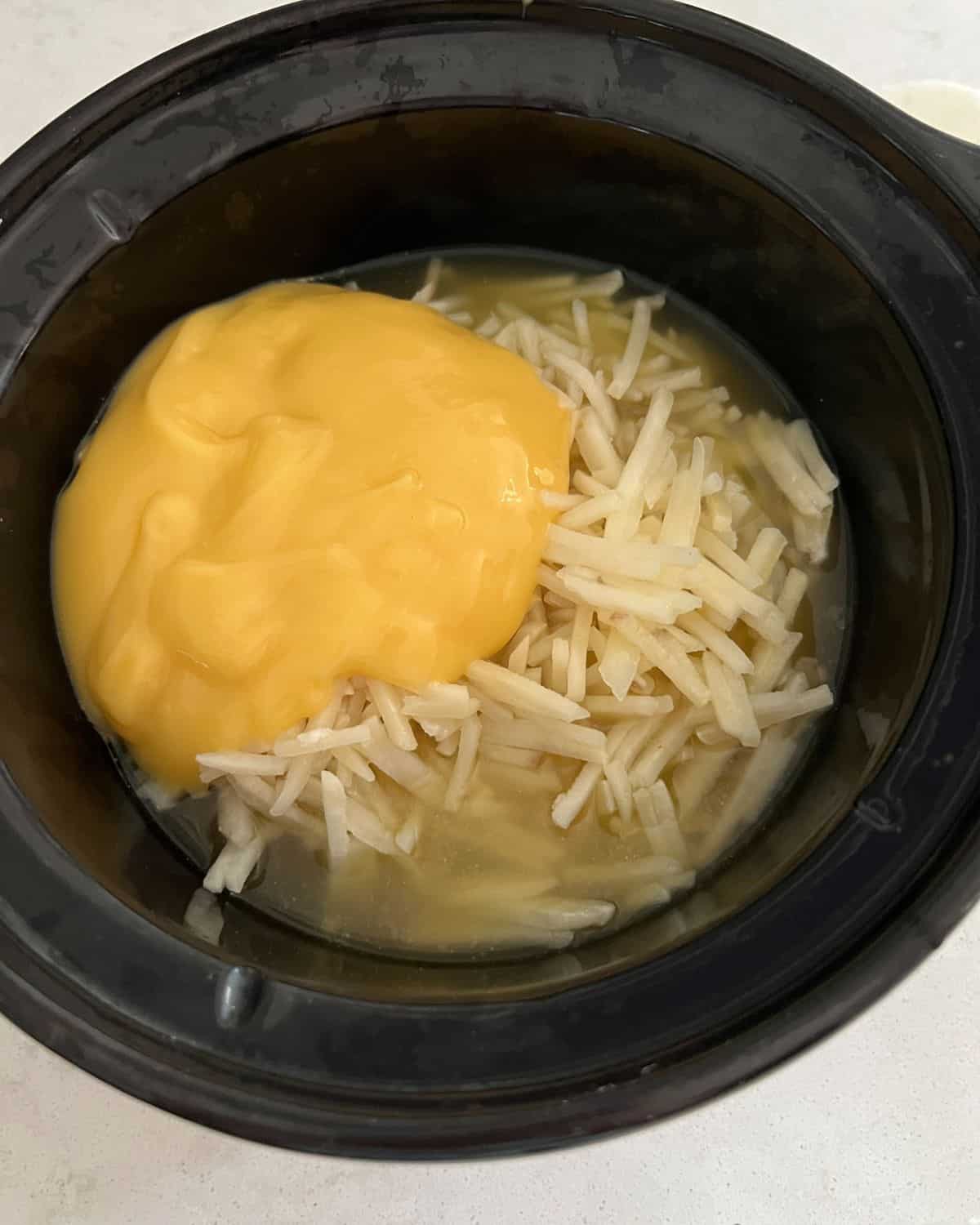 Condensed chicken soup, chicken stock, and hash browns in a crock pot. 