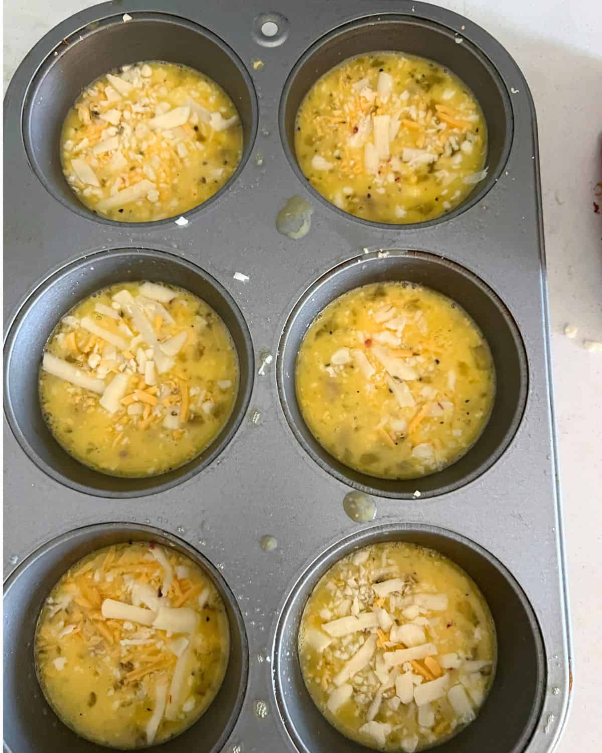 Egg mixture in a greased muffin pan. 