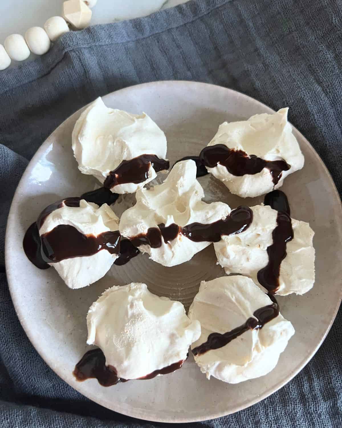 Frozen peanut butter cups with chocolate sauce on a grey plate. 