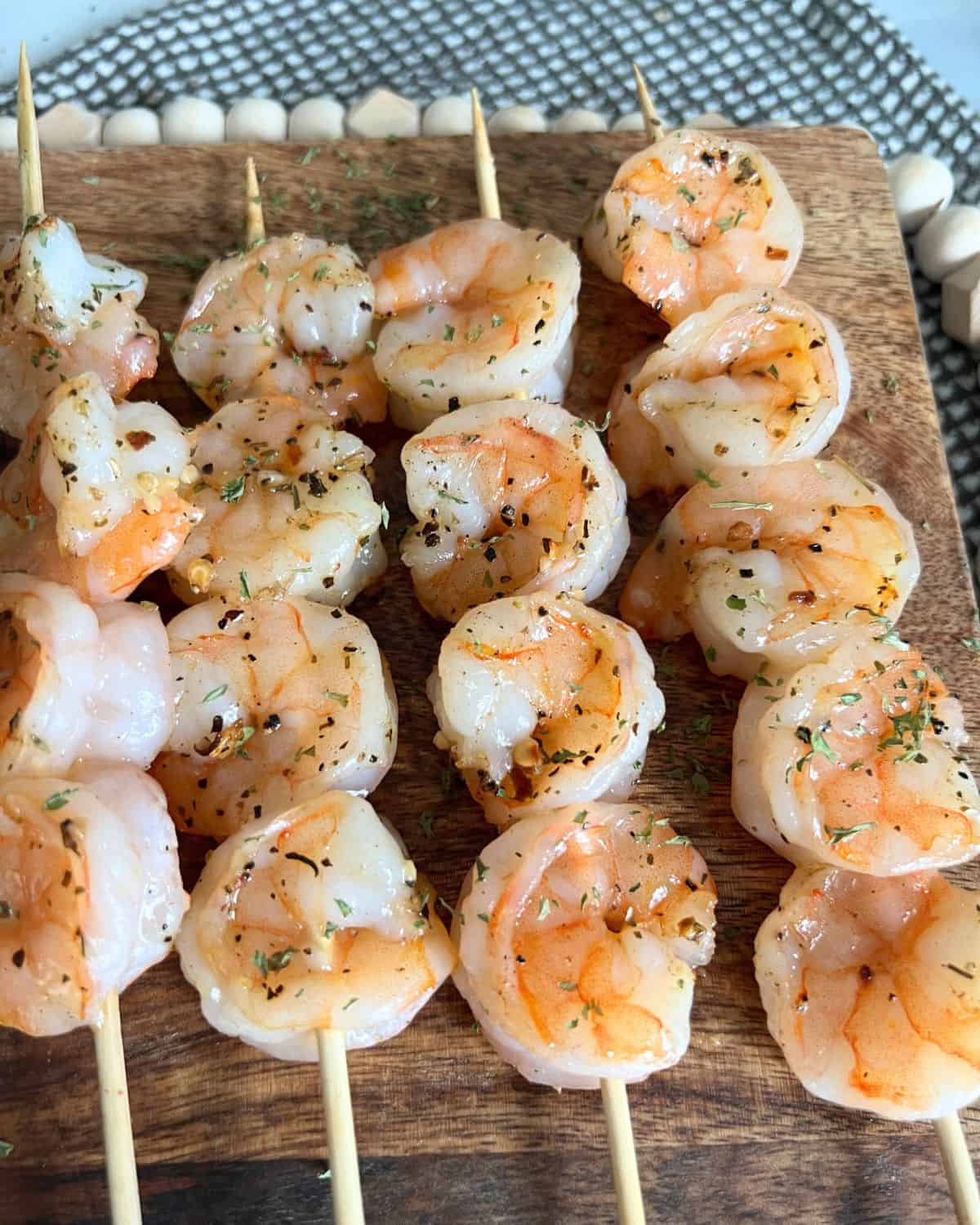Bobby Flay's grilled shrimp skewers on a wood cutting board. 