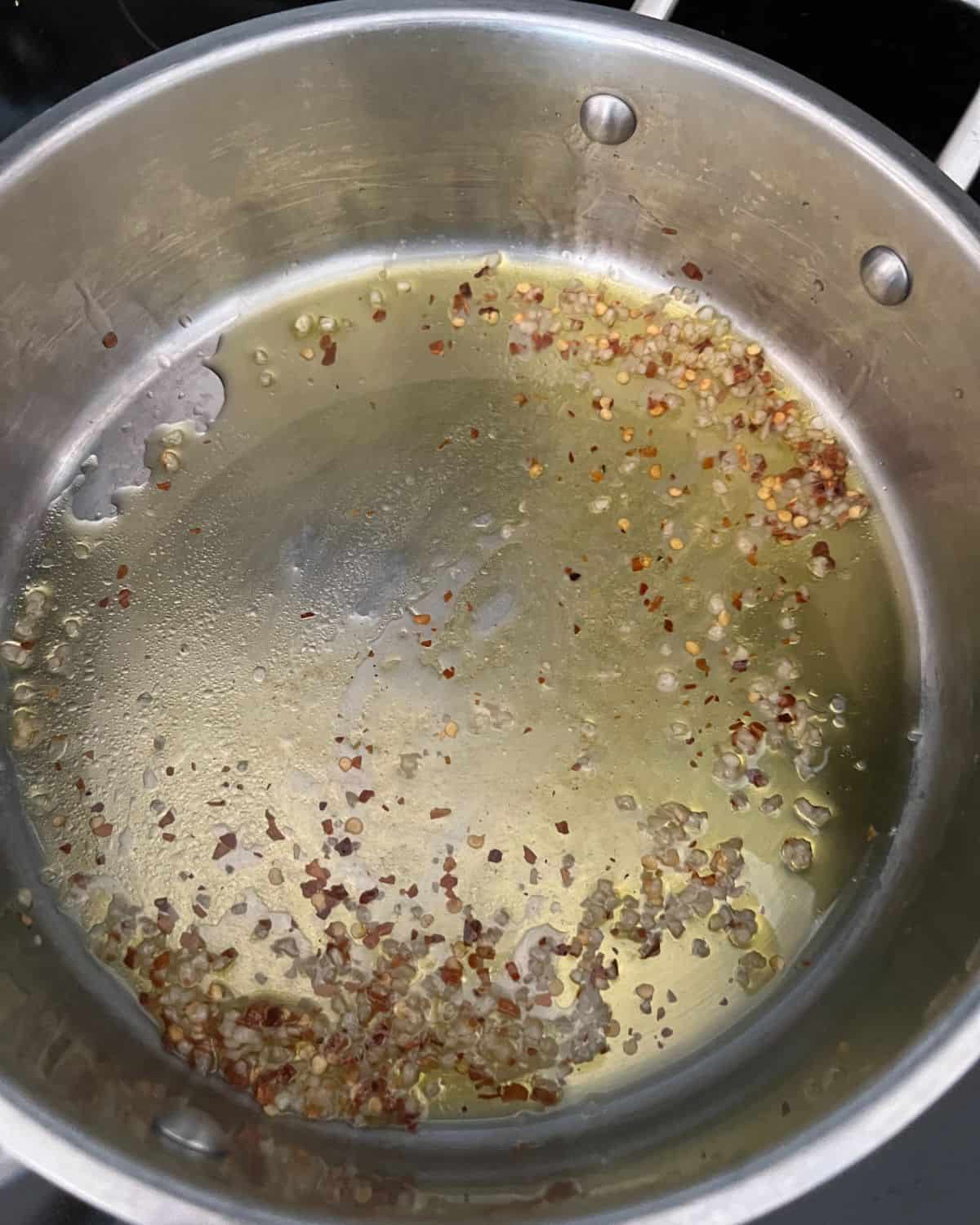 Olive oil, garlic, and chili flakes in a small pan.