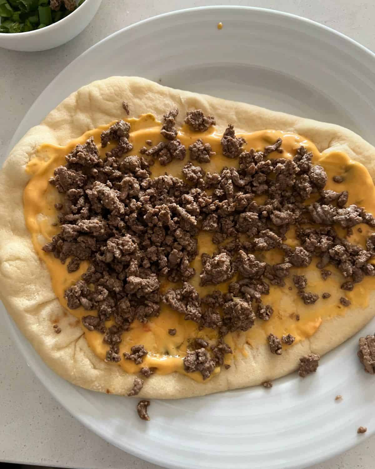 Naan bread topped with nacho cheese sauce and ground beef. 