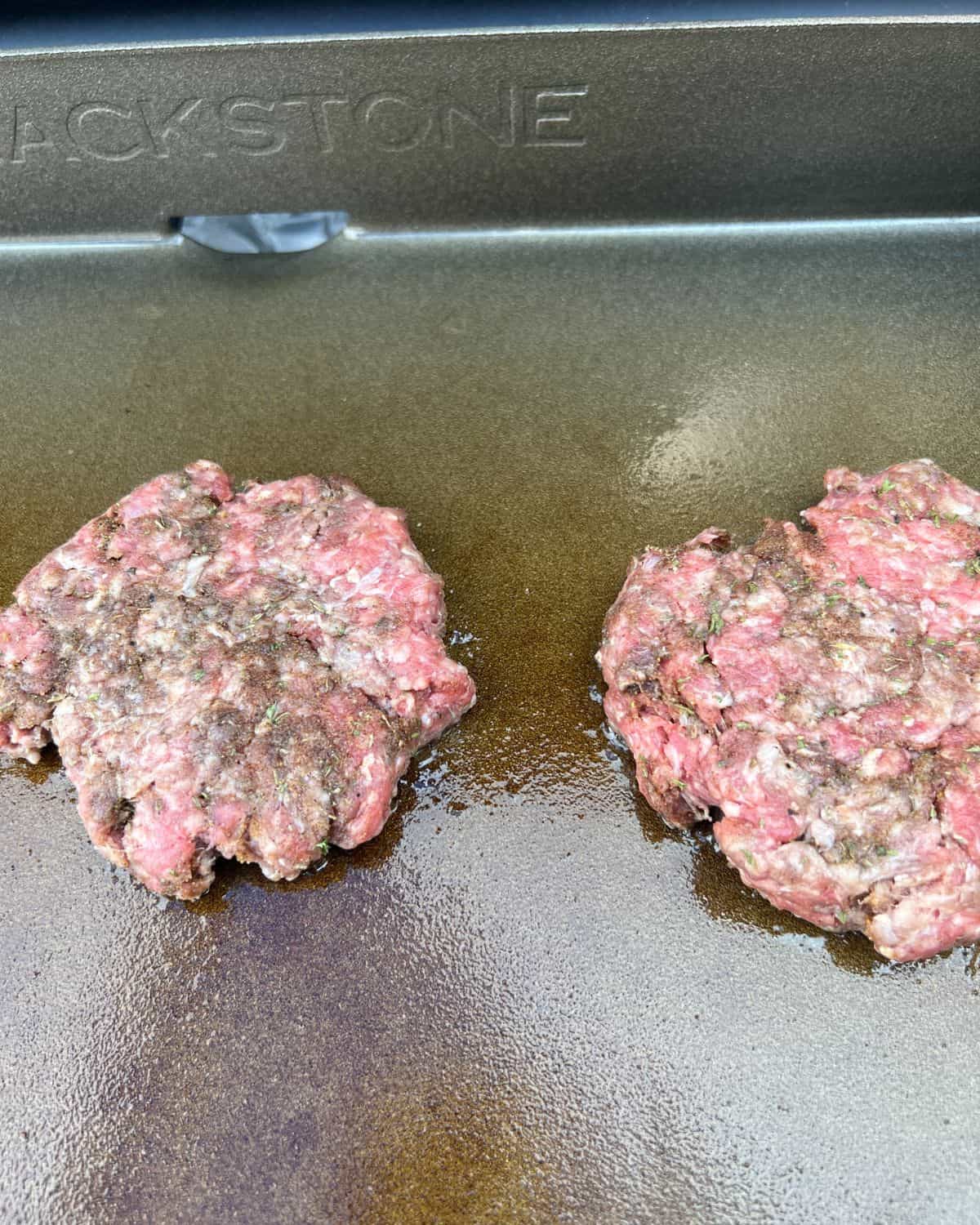 Jerk burgers cooking on a grill. 
