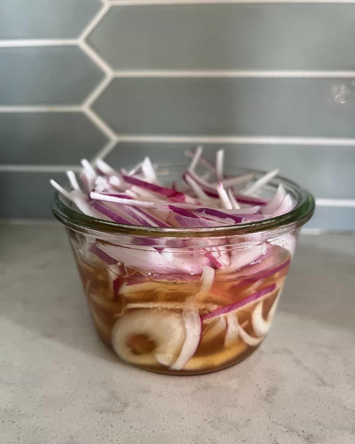 Vinegar mixture and red onions in a jar. 