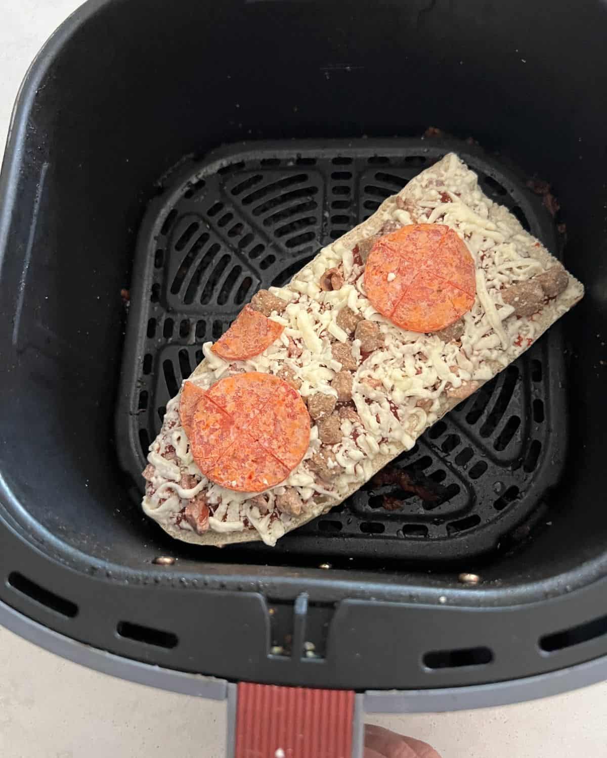 Frozen Red Baron pizza in air fryer basket. 