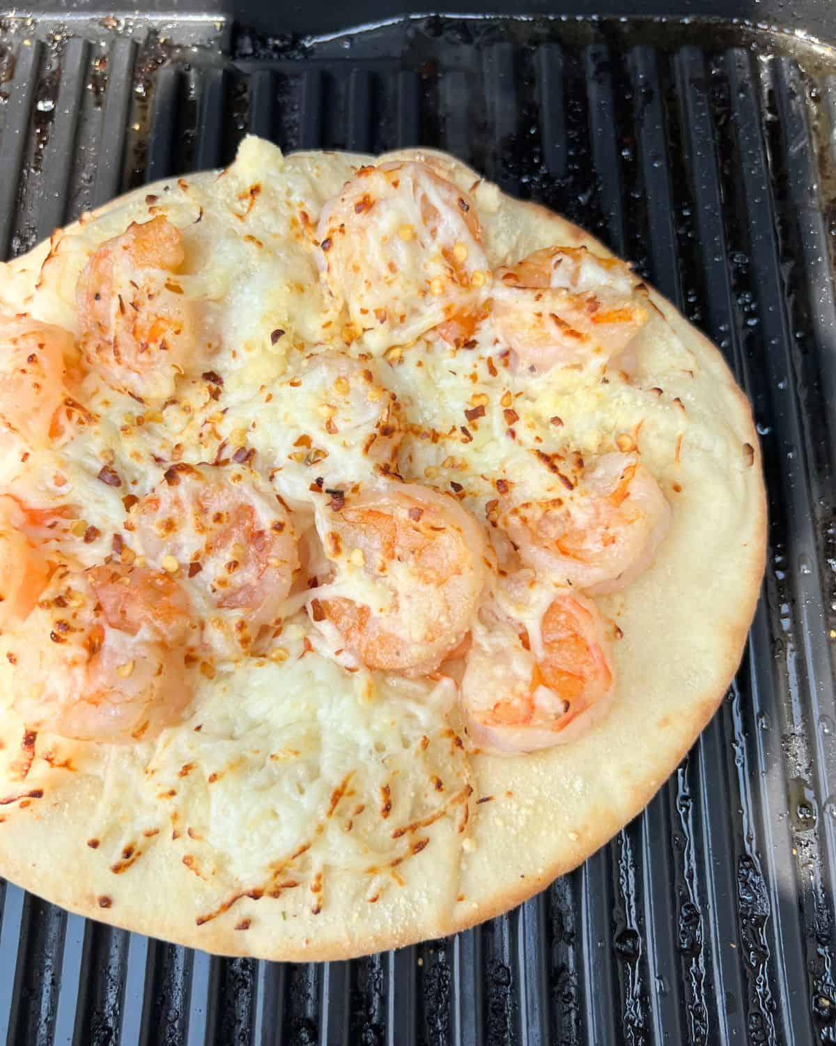 Shrimp scampi pizza on a grill set to high heat. 