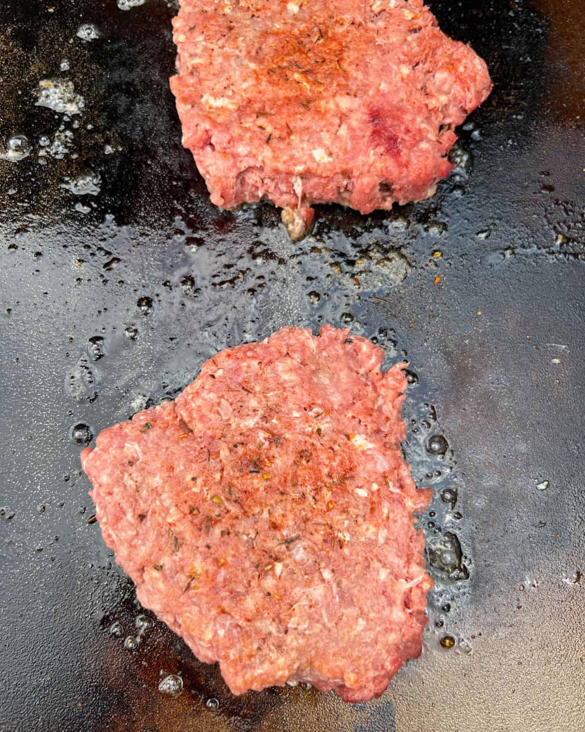 Smashed burger with seasoning on a Blackstone griddle. 