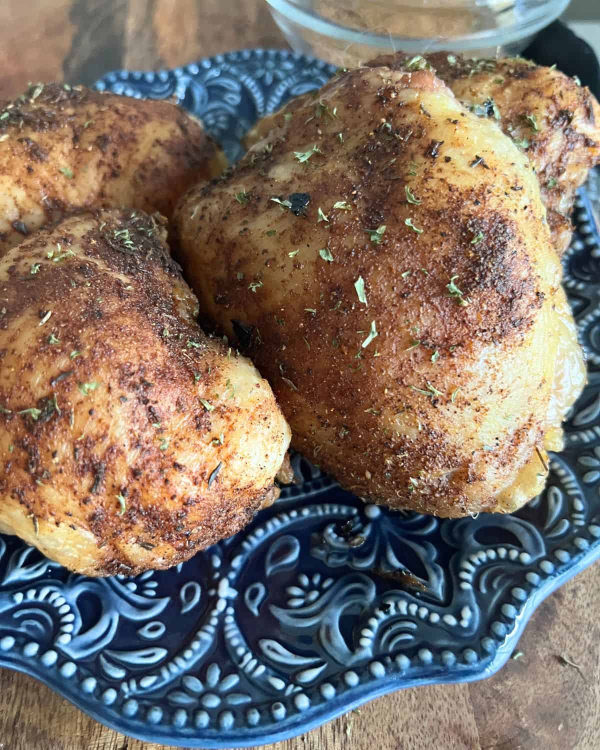 Spicy smoked chicken thighs on a blue plate. 