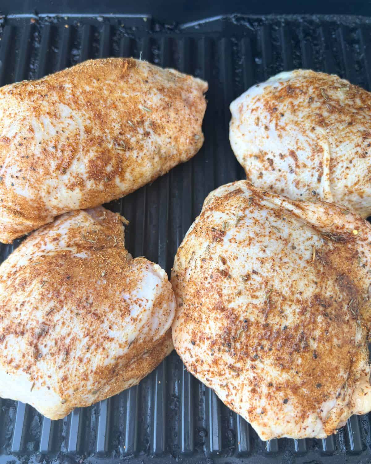 Seasoned chicken thighs on a smoker. 