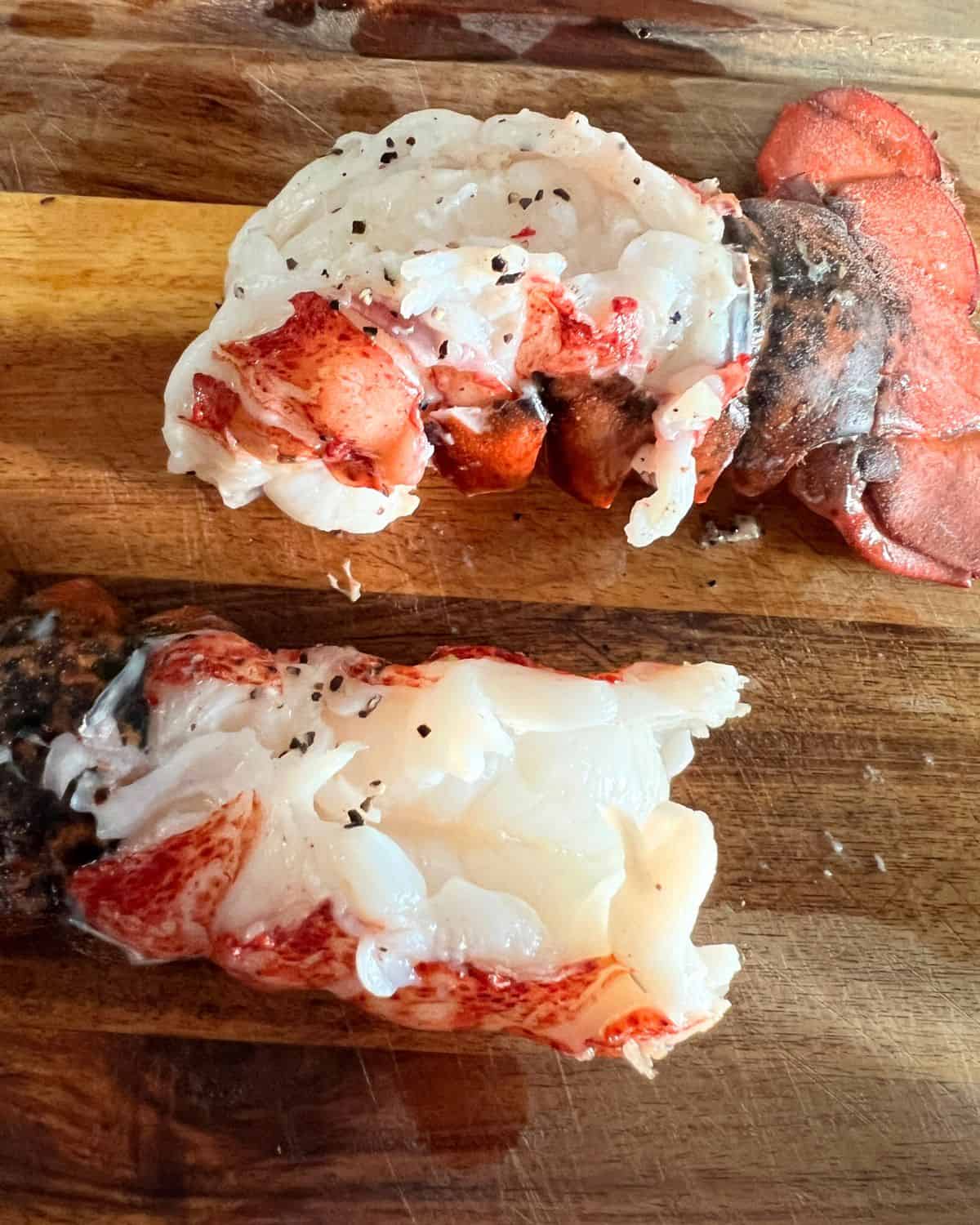 Seasoned smoked lobster tails on a wooden cutting board ready to eat or add to recipes. 