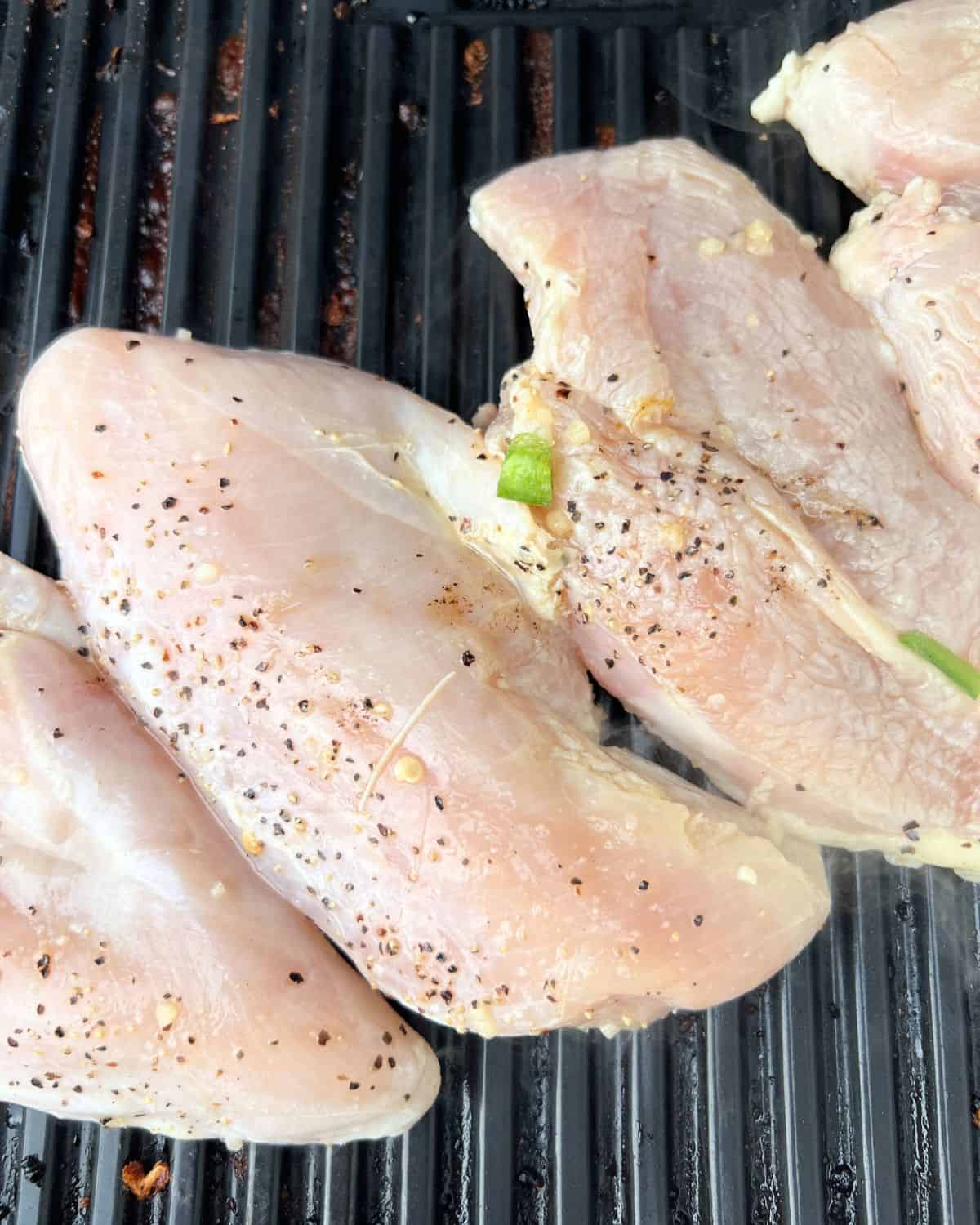 Tequila lime chicken on a grill top. half way cooked through. 