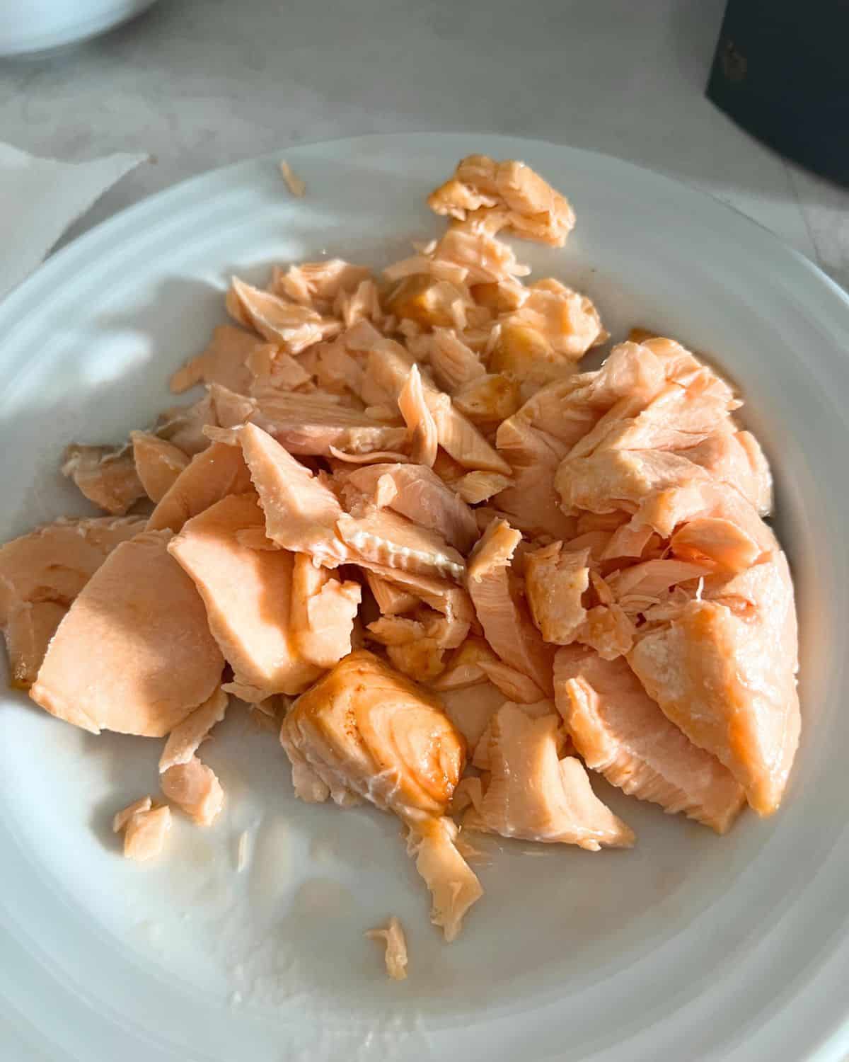 Flaked salmon on a white plate. 