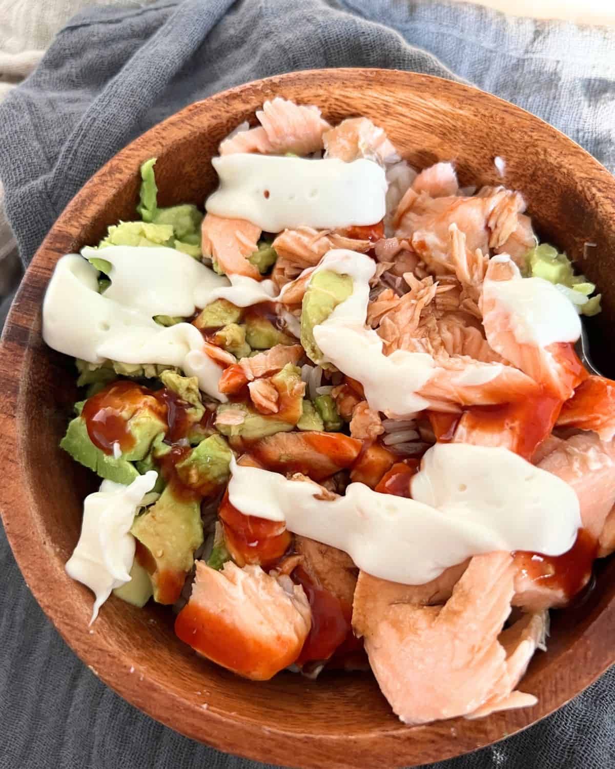Finished salmon bowl with mayo, hot sauce, and soy sauce. 