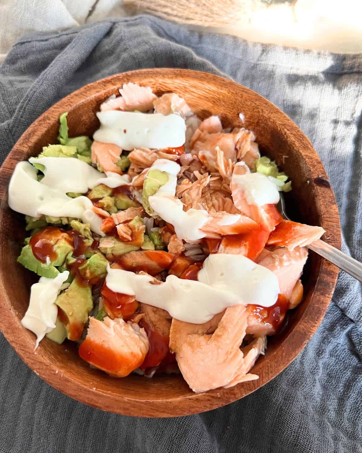 Salmon, rice, and avocado together in a wooden bowl. 