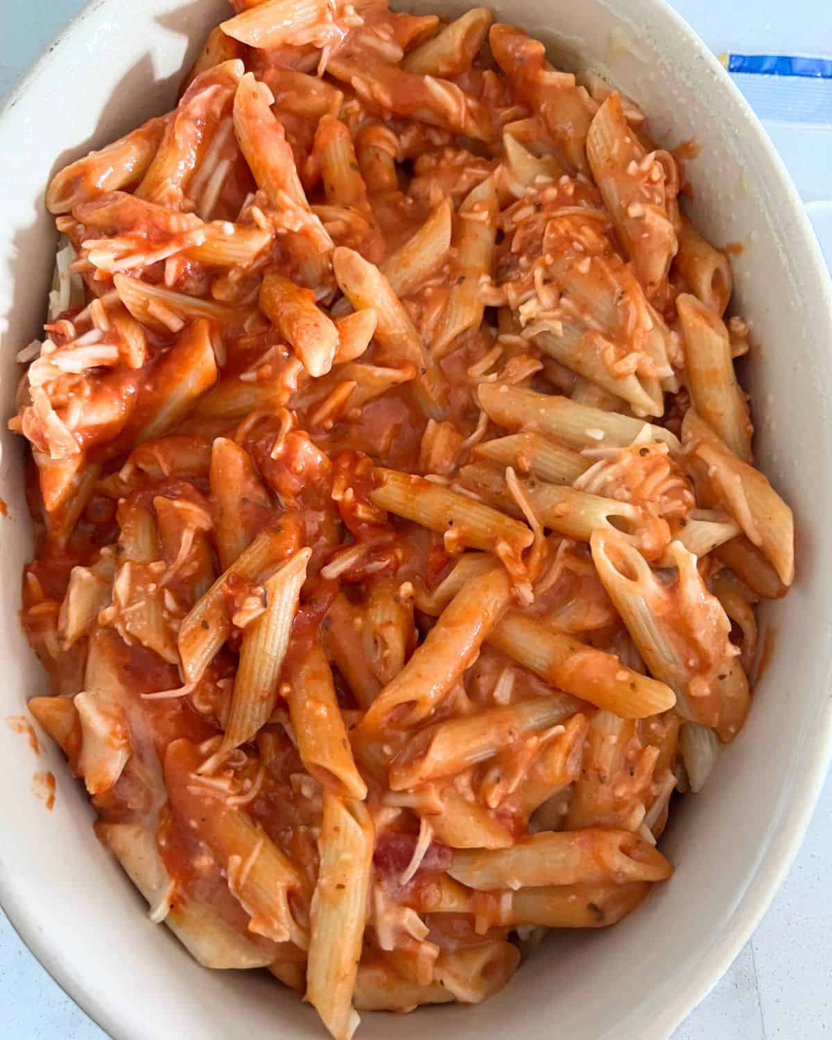 Noodles, cheese, and sauce in a baking dish.