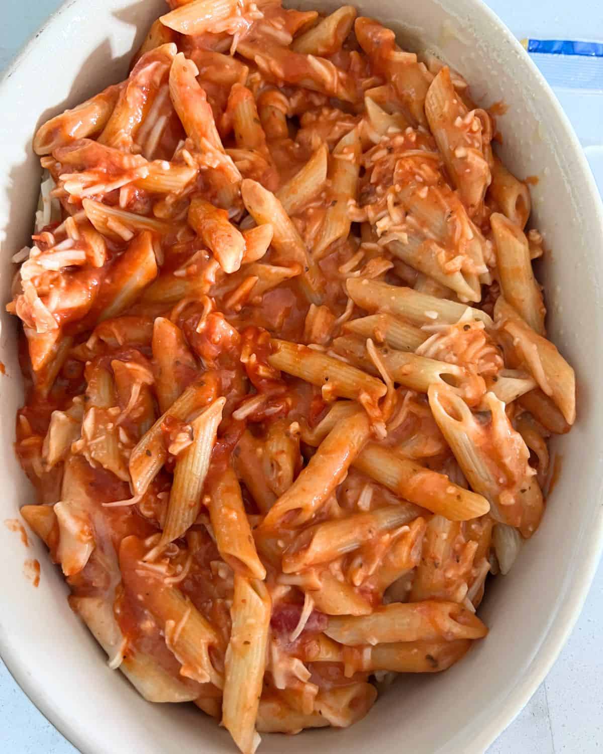 Noodles, cheese, and sauce in a baking dish. 