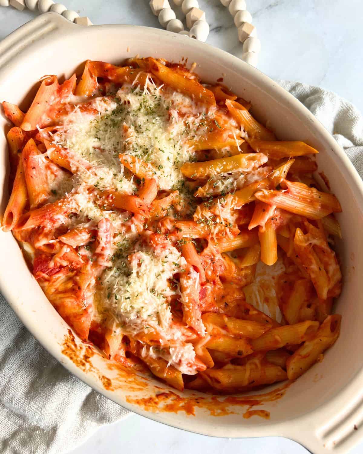 Pasta bake in casserole dish topped with parmesan cheese and parsley. 