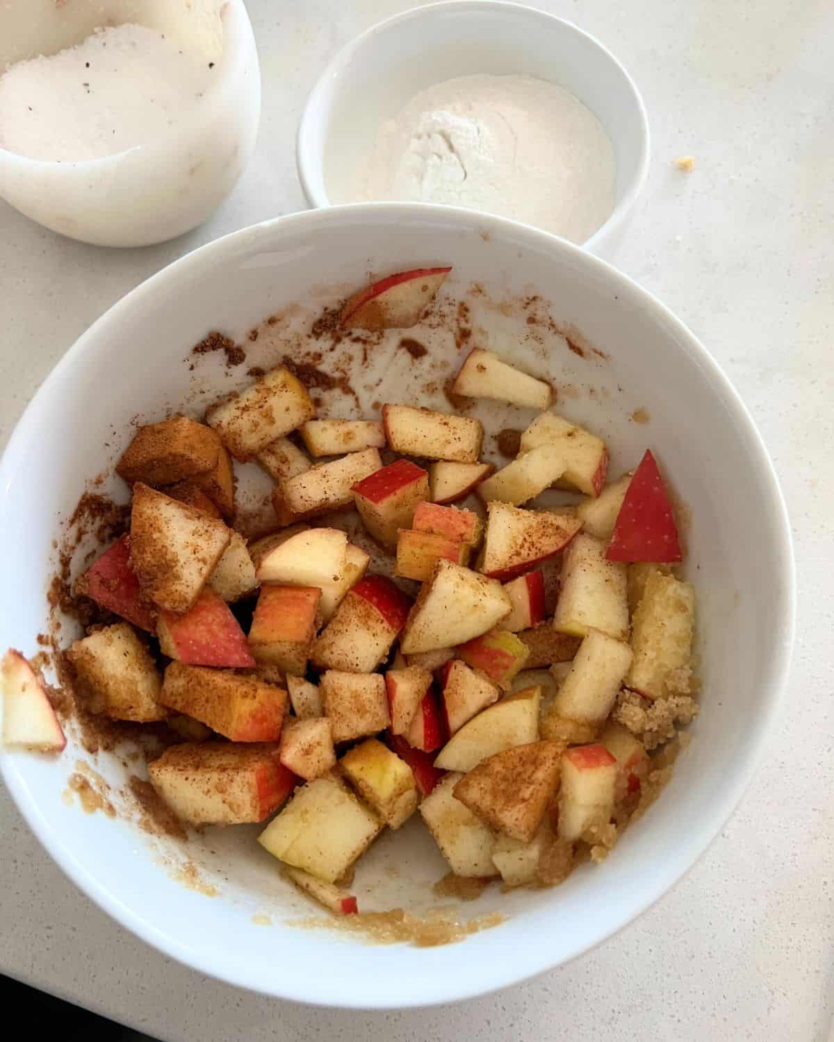 Apples with cinnamon and lemon juice in a white bowl. 