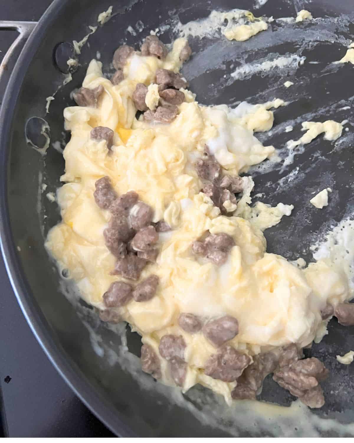 Eggs and sausage cooking in a skillet. 