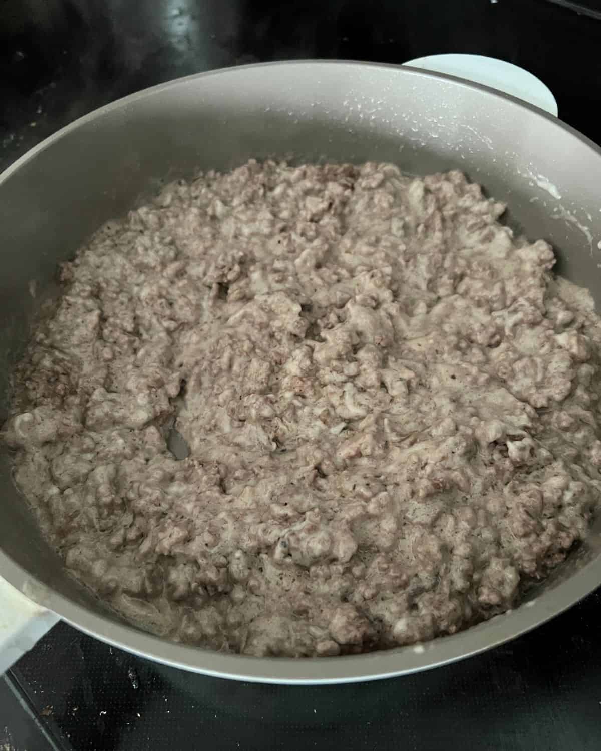 Seasonings, cream of mushroom, and ground beef in a skillet. 