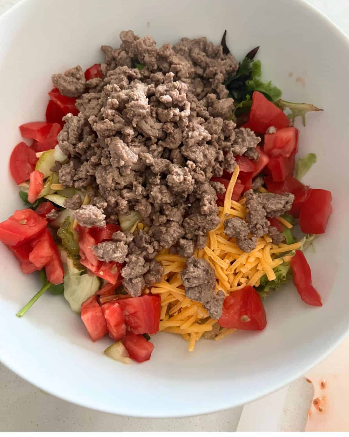 Ingredients for Big mac salad in a bowl. 