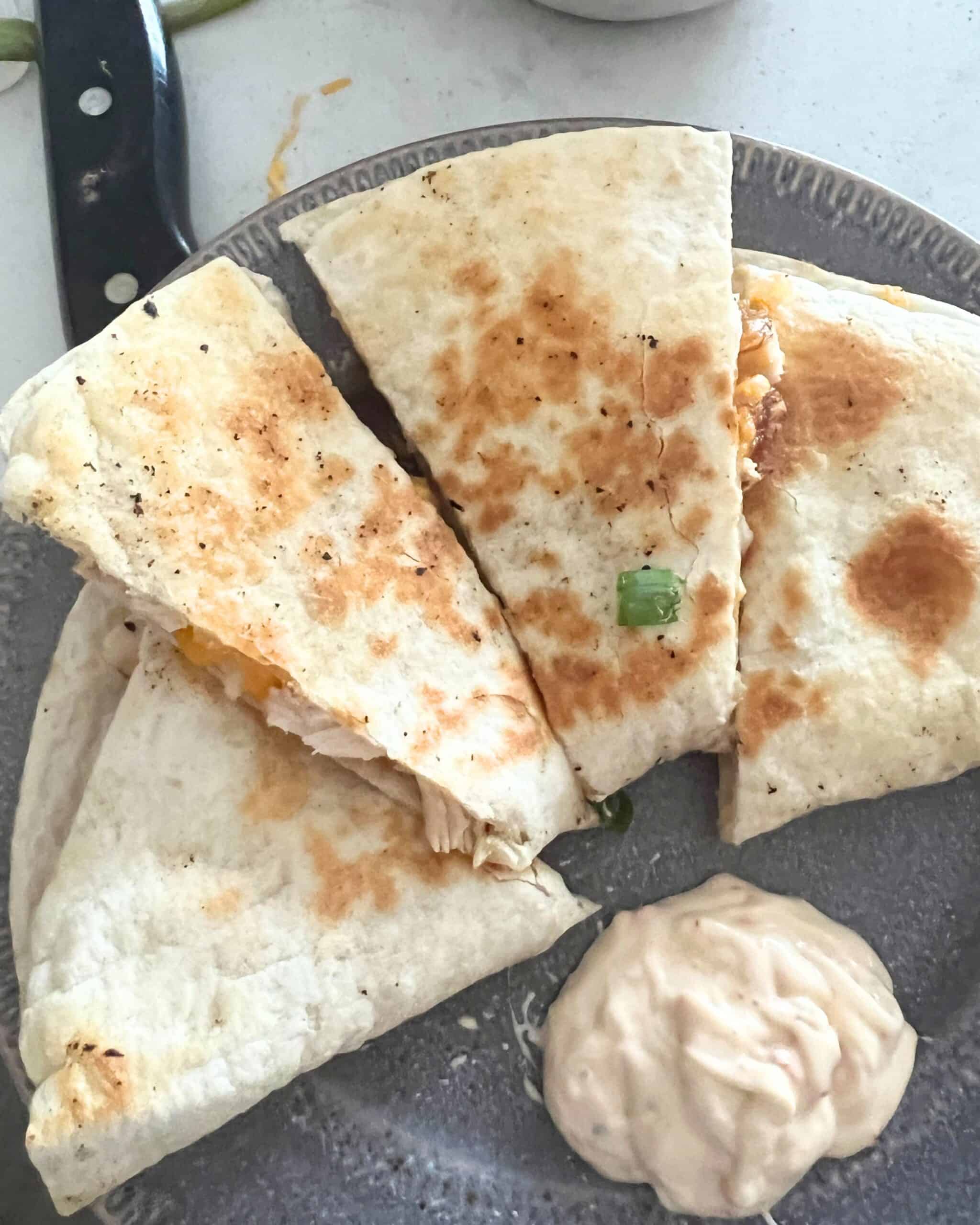 Blackstone Chicken quesadillas on a grey plate with Chipotle sauce. 