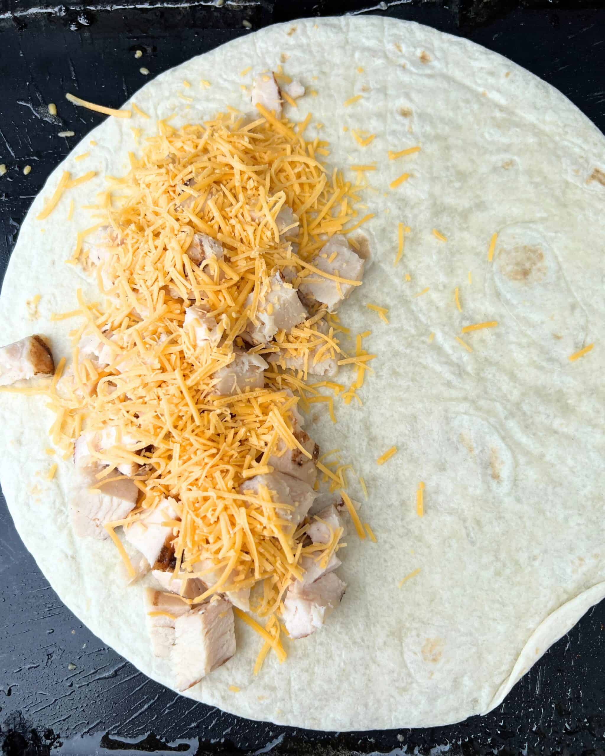 Cheese and chicken on top of a tortilla. 