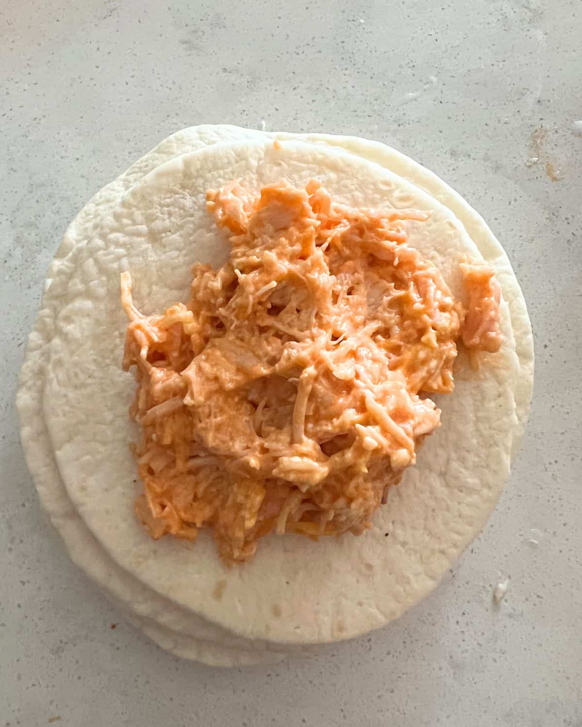 Buffalo chicken mixture on top of a tortilla. 