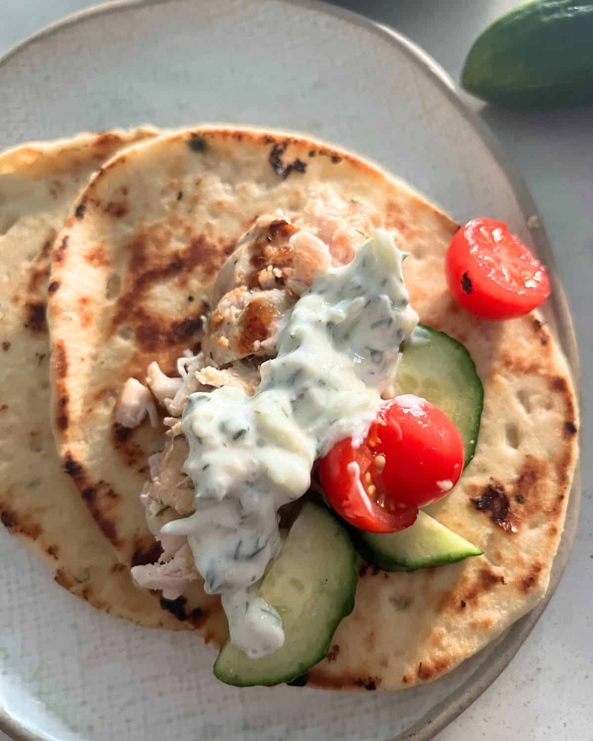 Grilled chicken gyros with Greek Tzatziki Sauce on a white plate. 