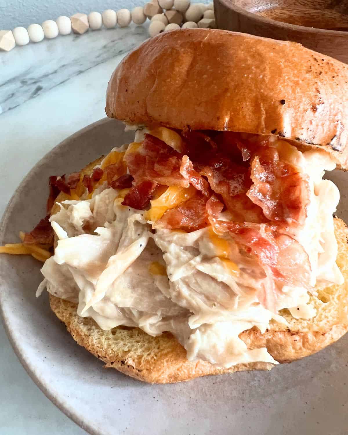 Slow cooker crack chicken in a bun on a white plate. 