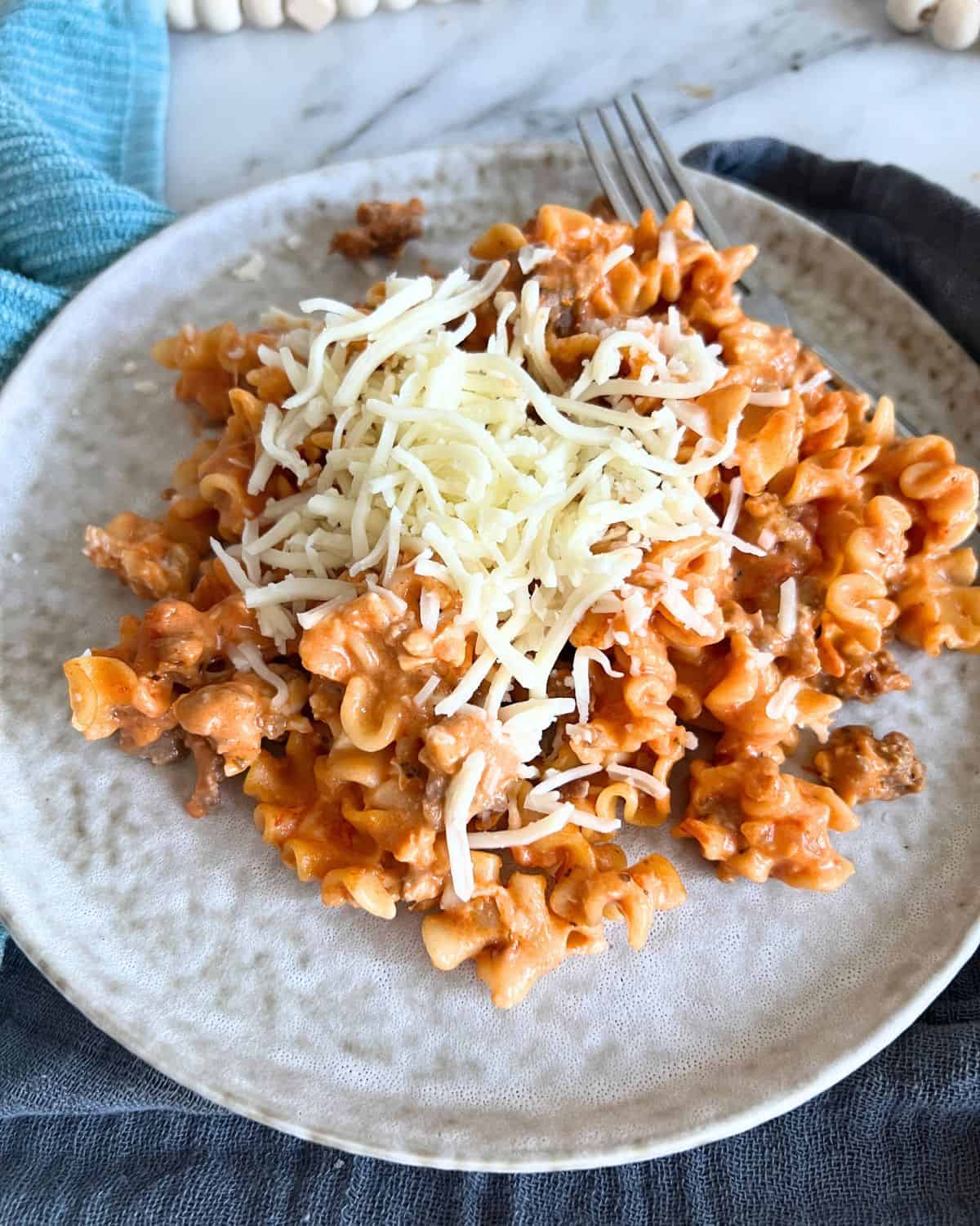 Lasagna pasta topped with cheese on a grey plate.
