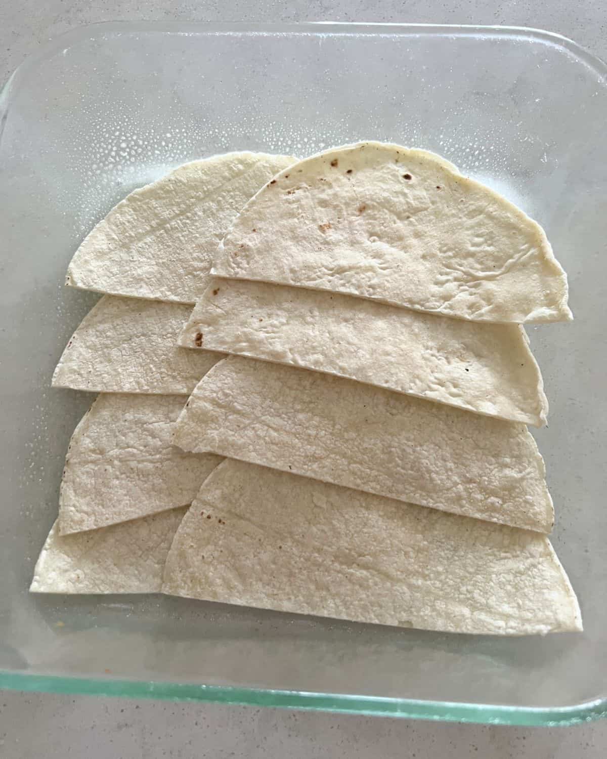 Tortillas layered on the bottom of a dish. 