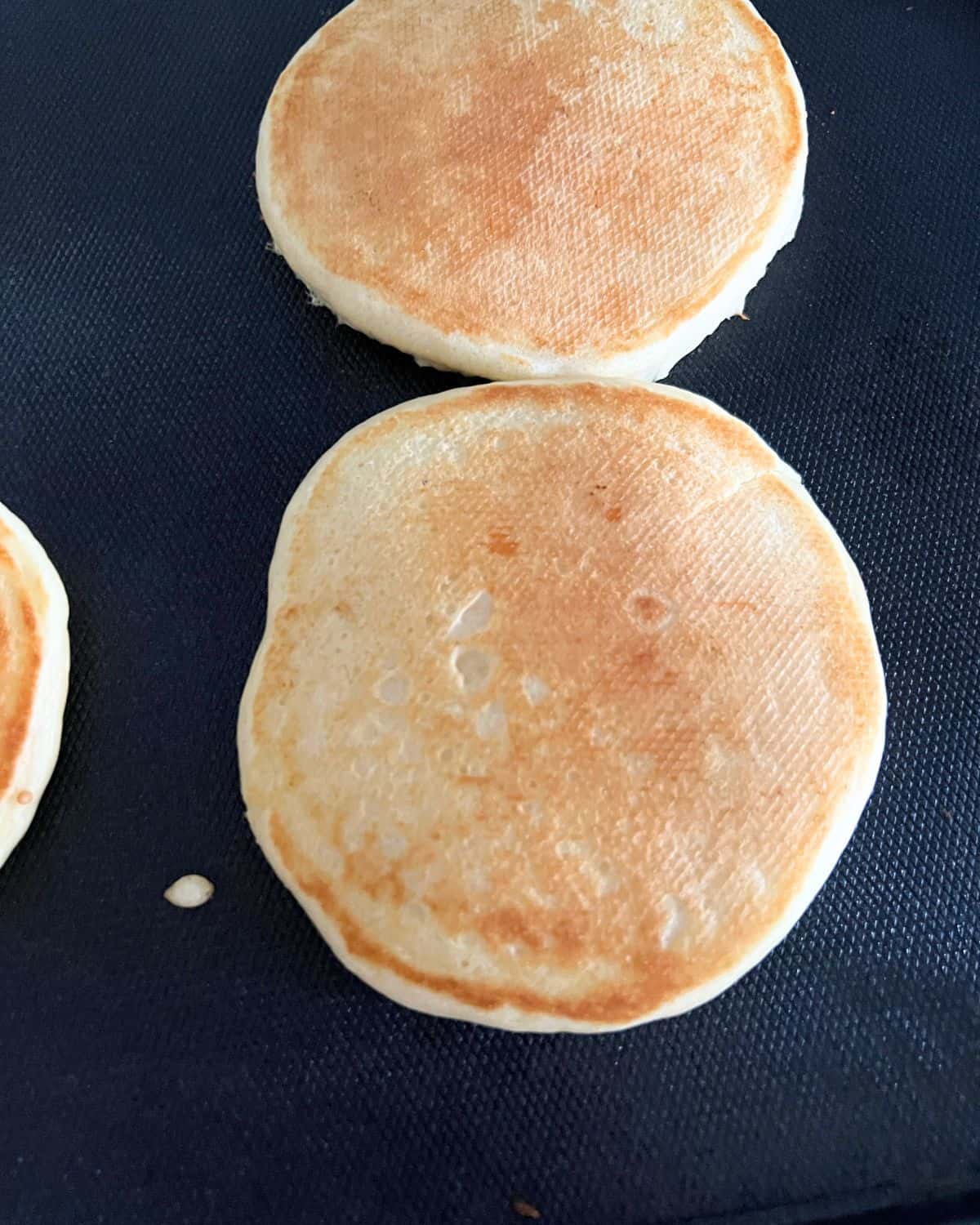 Pancakes cooking on a griddle. 