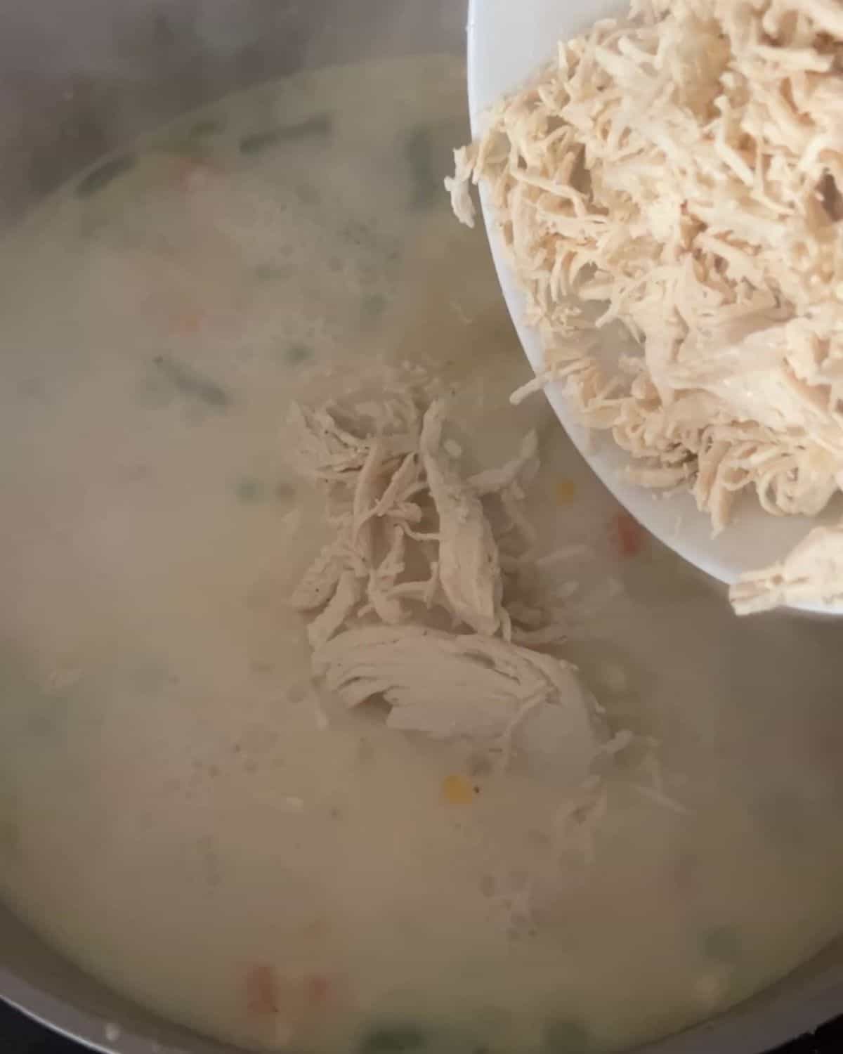 Chicken being poured over gravy mixture. 