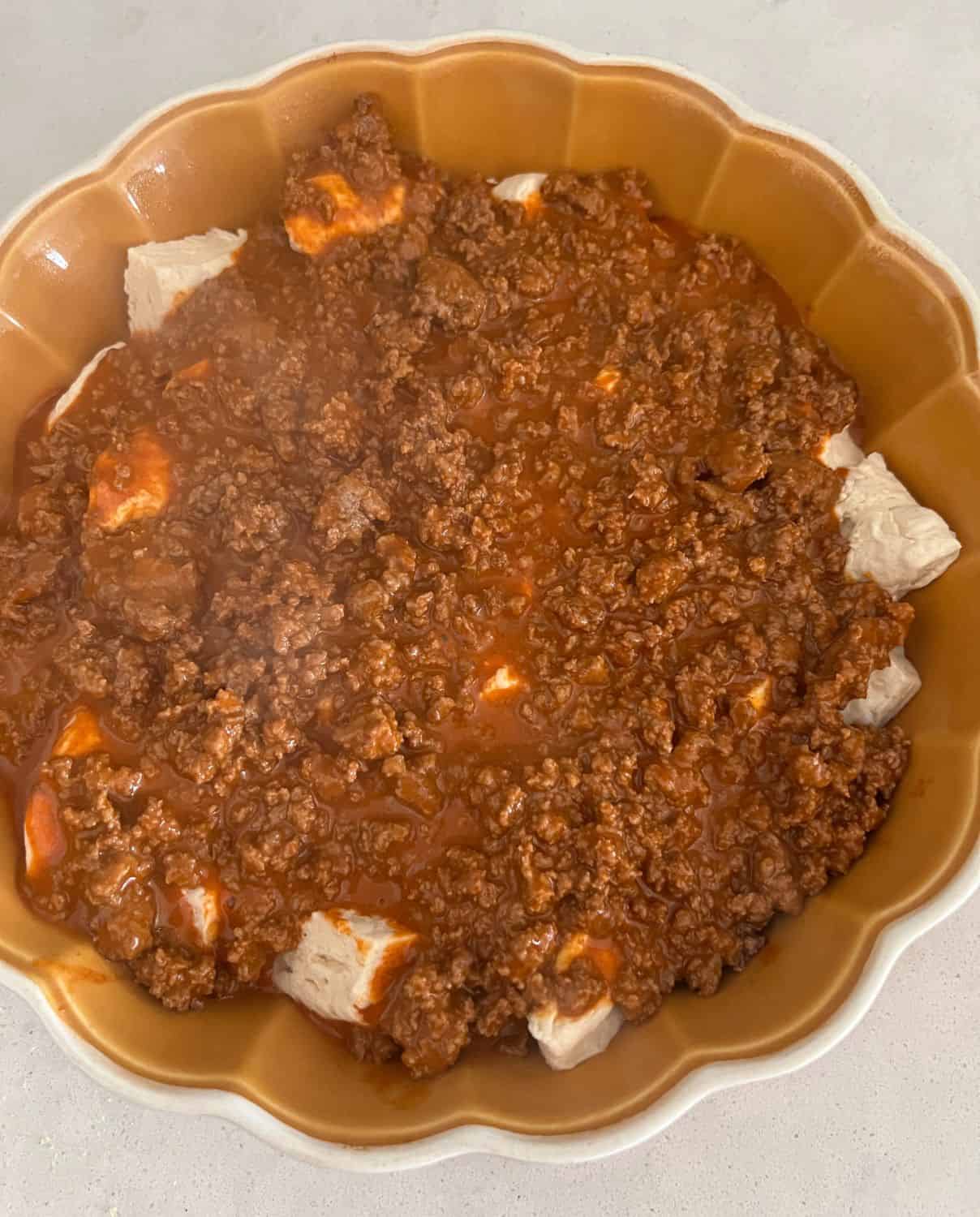 Ground beef mixture over the top of layered biscuits in a casserole dish. 