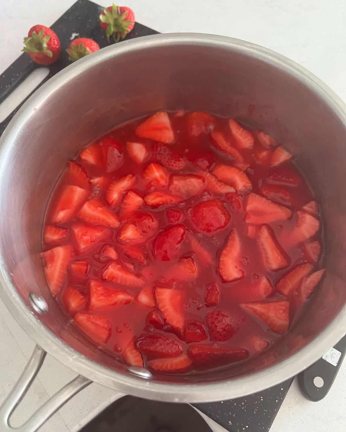 Strawberries and gelatin combined in a pan. 