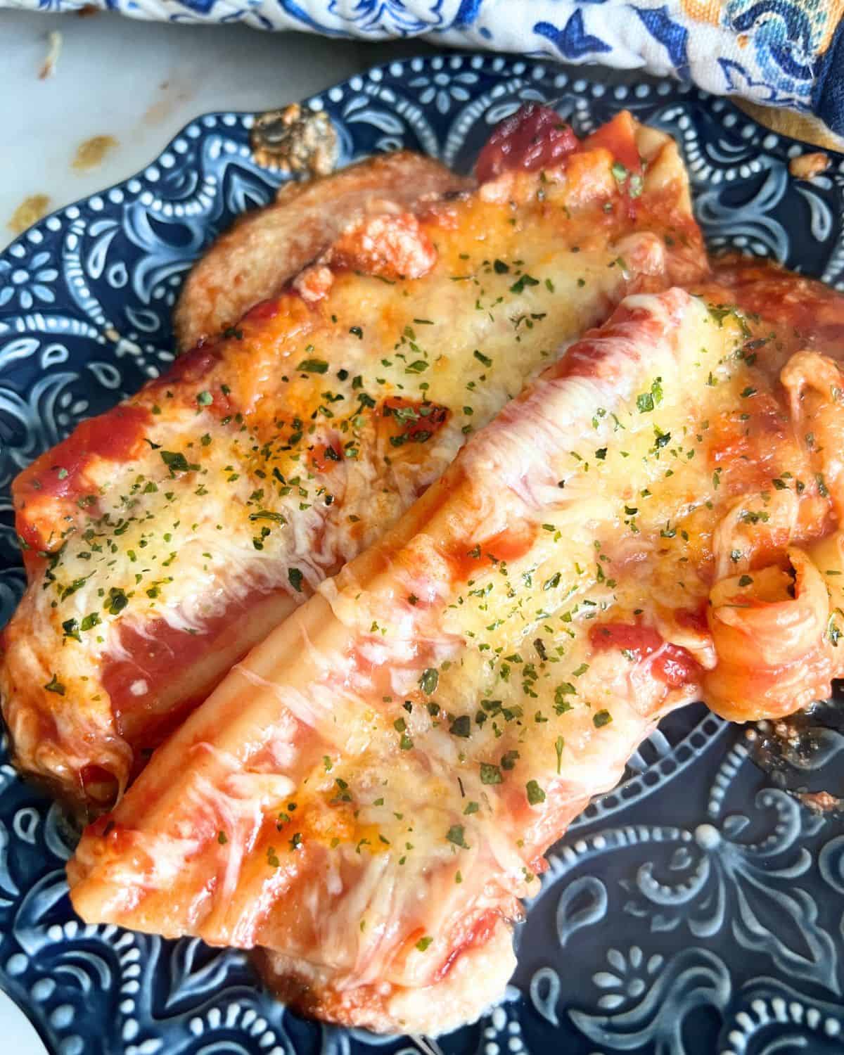 Cheese stuffed manicotti on a blue plate. 