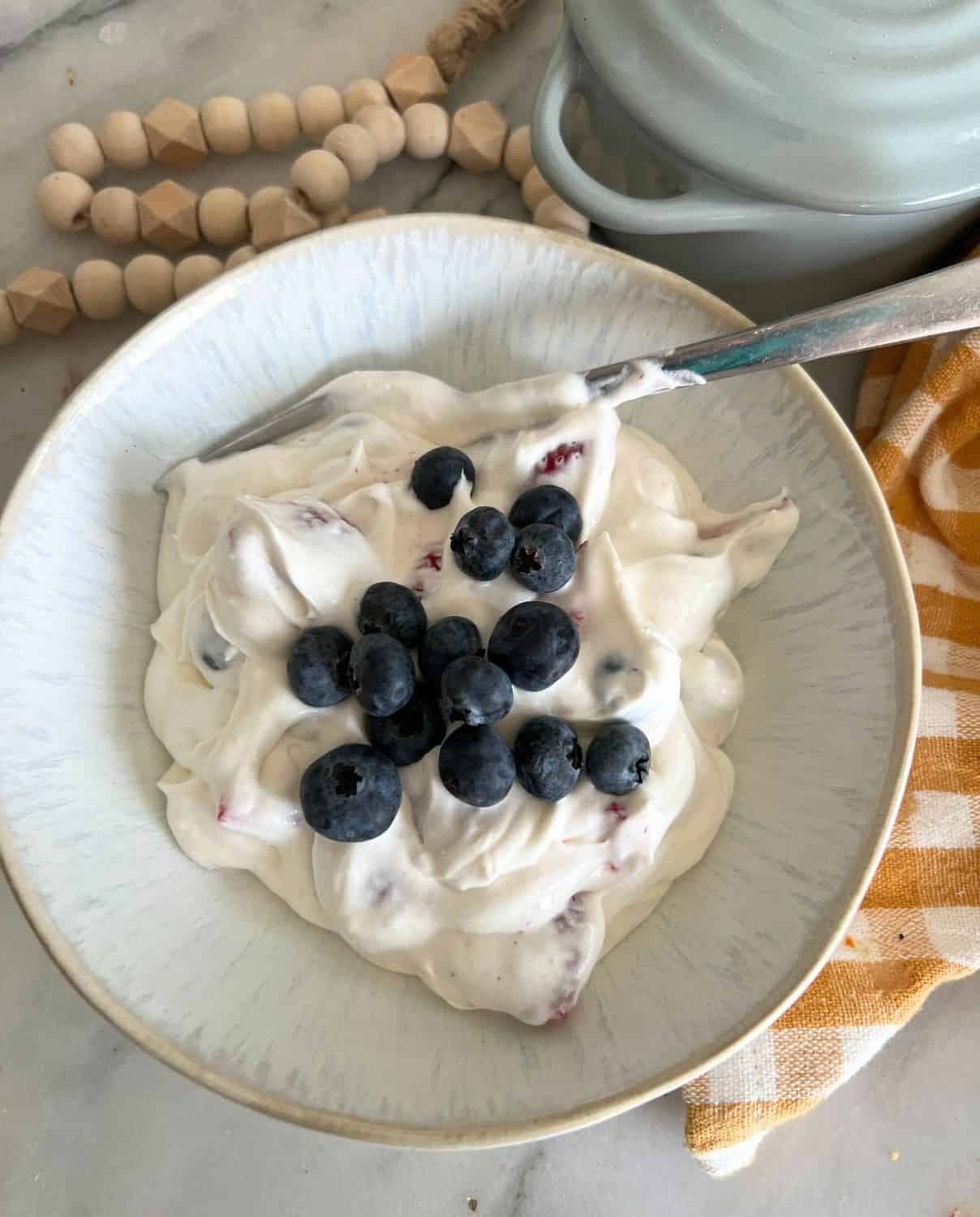 Berry cheesecake salad in a bowl topped with fresh blueberries. 